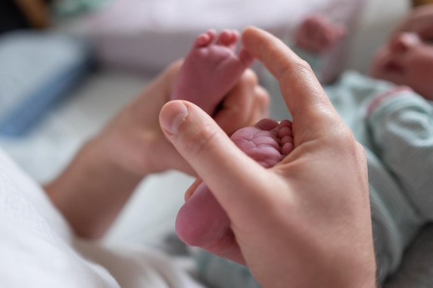 Pieds de bébé dans les mains du père. Parent massant la jambe du nouveau-né.