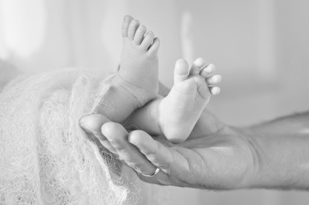 Pieds de bébé dans les mains du père Petits pieds de bébé nouveau-né sur les mains en forme de mâle gros plan Papa et son enfant