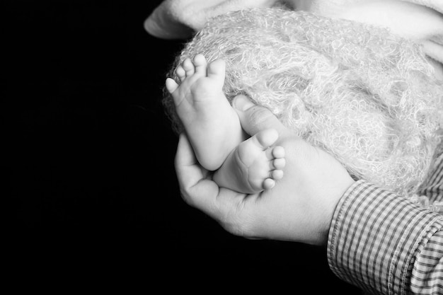 Pieds de bébé dans les mains du père Petits pieds de bébé nouveau-né sur les mains mâles gros plan Papa et son enfant Concept de famille heureuse Belle image conceptuelle de la parentalité