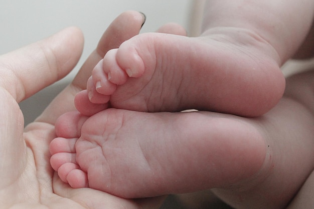 Pieds de bébé dans les mains de maman gros plan nouveau-né