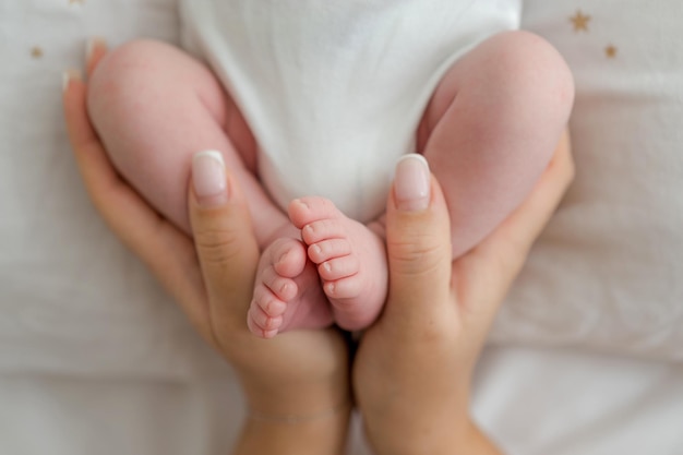 Pieds de bébé dans les mains de la mère idée de photographie nouveau-né sur fond blanc. Naturel, blanc et simple