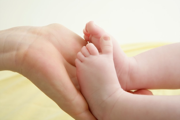 Pieds de bébé dans les mains de la mère jouant