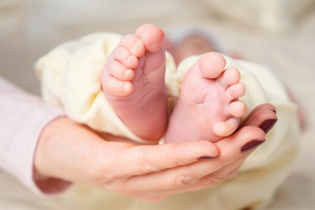 Pieds de bébé dans les mains de la mère. Maman et son enfant. Notion de famille heureuse. Belle image conceptuelle de la maternité