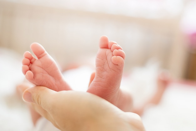 Pieds de bébé dans les mains de la mère. Maman et son enfant. Notion de famille heureuse.