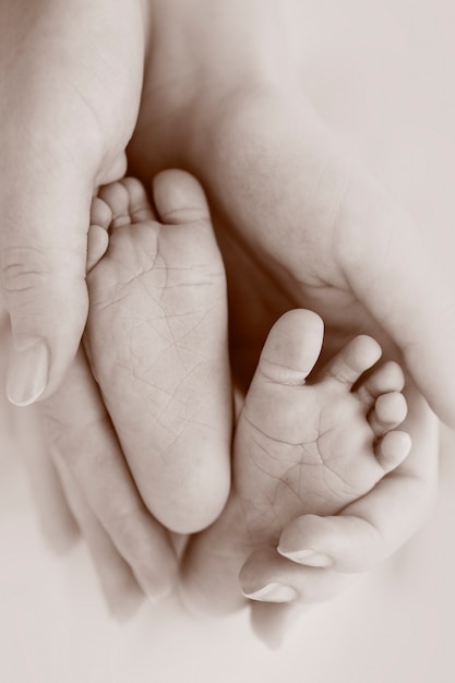 Pieds de bébé dans les mains de la mère. Petit bébé nouveau-né