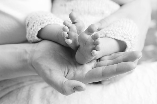 Pieds de bébé dans les mains de la mère Petits pieds de bébé nouveau-né sur les mains en forme de femme agrandi Maman et son enfant Concept de famille heureuse Belle image conceptuelle de la maternité