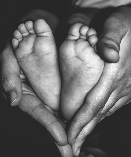 Pieds De Bébé Dans Les Mains De La Mère.