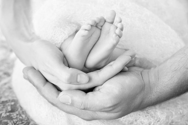 Pieds de bébé dans les mains des parents Petits pieds de bébé nouveau-né sur les mains en forme de parents gros plan Les parents et eux