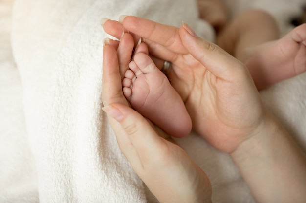 pieds de bébé nouveau-né dans les mains de la mère