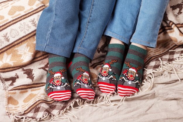 Pieds en chaussettes de Noël sur plaid de Noël. Couple assis sur la couverture, se détend en se réchauffant les pieds dans des chaussettes en laine. Vacances d'hiver et de Noël concep