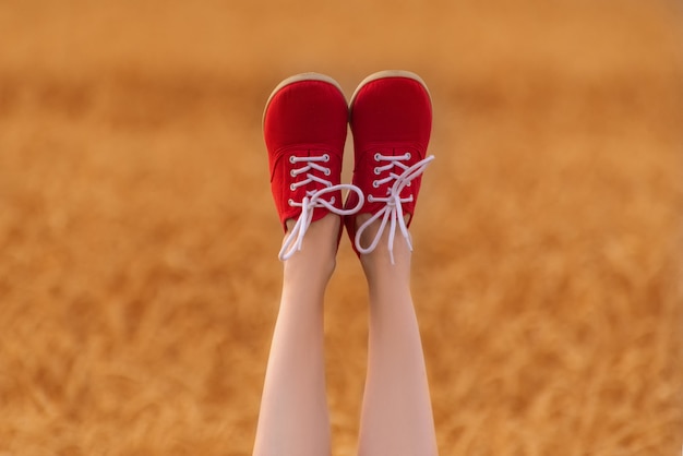 Pieds en chaussures rouges vers le haut. Jambes féminines minces sur champ de blé.