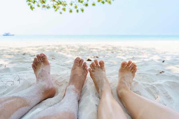 Les pieds d'un couple assis sur la plage qui s'étend vers la mer