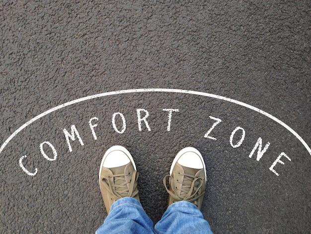 pieds dans des chaussures de toile debout à l'intérieur de la zone de confort - pied selfie du point de vue personnel - texte à la craie sur l'asphalte