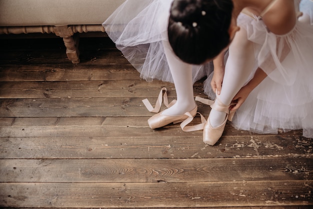 Pieds de danseuse de ballet sur le sol du studio. Danseuse adolescente met copyspace ballerines.