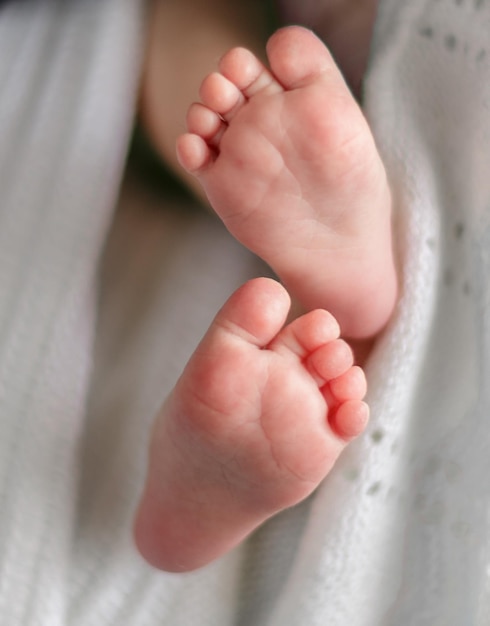 Les pieds du bébé enveloppés dans une couverture blanche se bouchent