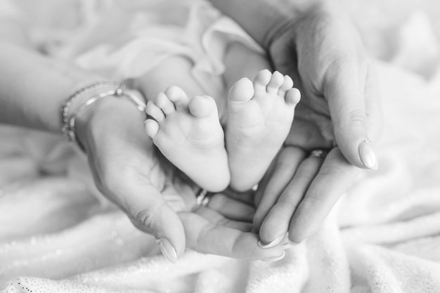 Les pieds du bébé nouveau-né dans les mains de la mère forment comme un joli coeur Mère tenant les jambes de l'enfant dans les mains Image en gros plan Concept de famille heureuse