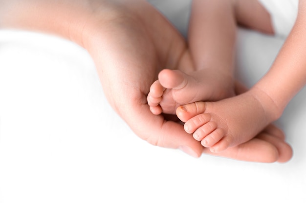 Les pieds du nouveau-né entre les mains de maman se bouchent. Maman et son enfant. Une belle image conceptuelle de la maternité.