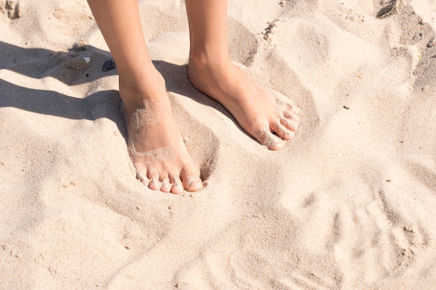 Les pieds de l'enfant dans le sable