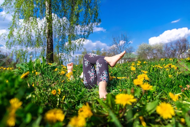 Pieds d'enfant sur l'herbe dans le jardin de pissenlits de printemps Mise au point sélective