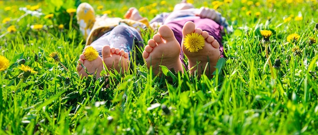 Pieds d'enfant sur l'herbe dans le jardin de pissenlits de printemps Mise au point sélective