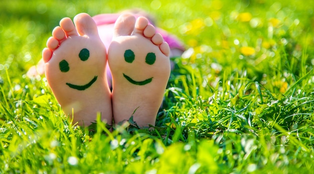 Pieds d'enfant sur l'herbe dessinant un sourire