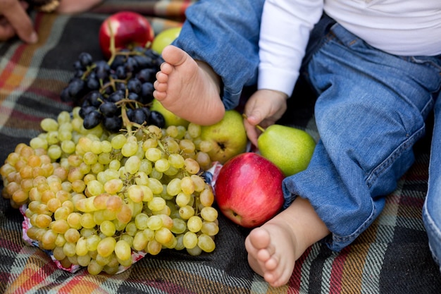 Les pieds d'un enfant sont devant un bouquet de fruits.
