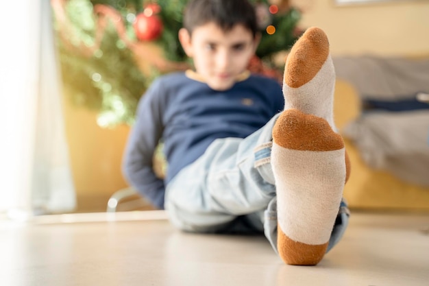 Pieds d'enfants dans des chaussettes de Noël, allongés près d'un arbre de Noël, profitant de la période de Noël