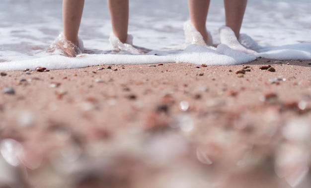 Pieds d'enfants dans l'eau de mer sur la plage