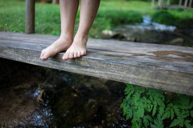 Pieds d&#39;enfants debout sur le pont de bois dans le ruisseau de montagne