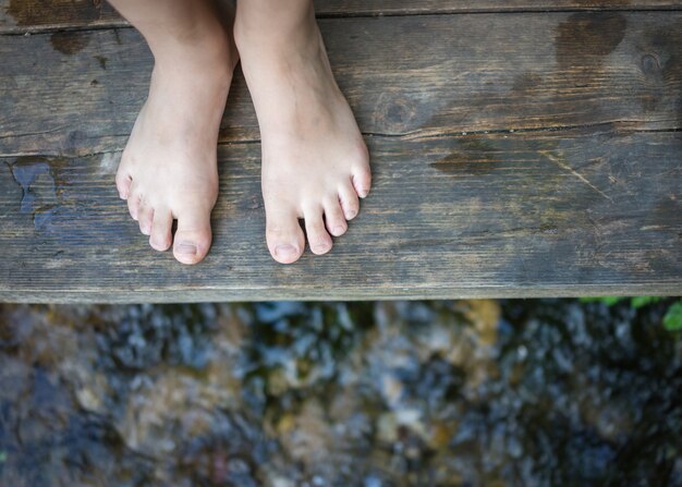 Photo pieds d'enfants debout sur le pont de bois dans le ruisseau de montagne