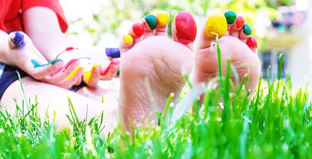 Les pieds des enfants avec un motif de peintures sourient sur l'herbe verte. Mise au point sélective. la nature.