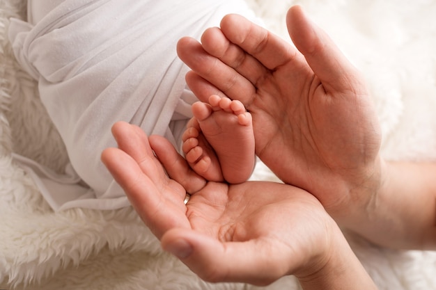 Les pieds des enfants tiennent la main de la mère et du père. Mère, père et enfant. Concept de famille heureuse. photo de haute qualité