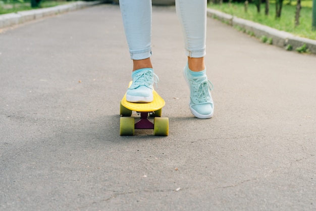 Pieds féminins en baskets sur un skateboard sur asphalte