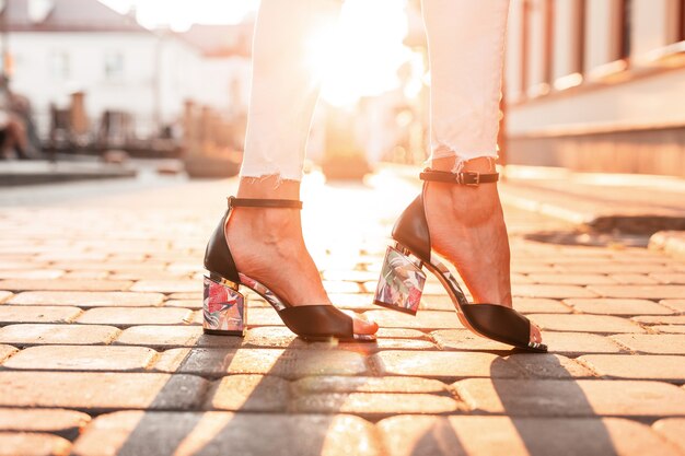 Pieds féminins avec des chaussures noires à la mode dans la ville au coucher du soleil