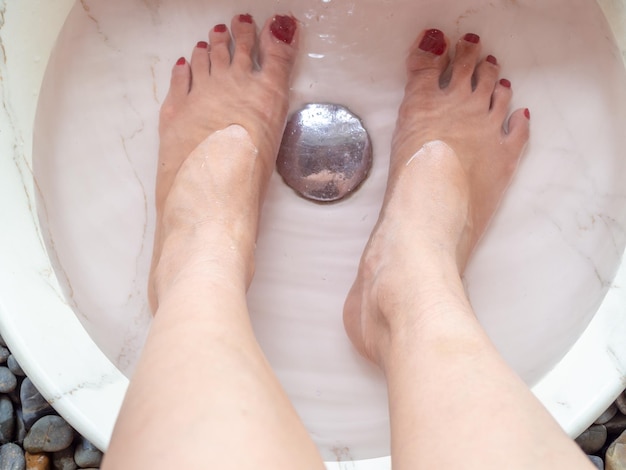 Pieds féminins dans le bassin en marbre du spa pour les pieds