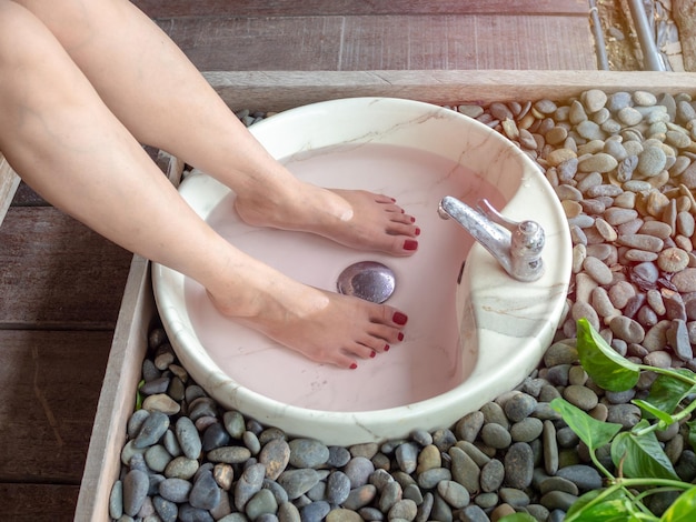 Pieds féminins dans le bassin en marbre du spa pour les pieds