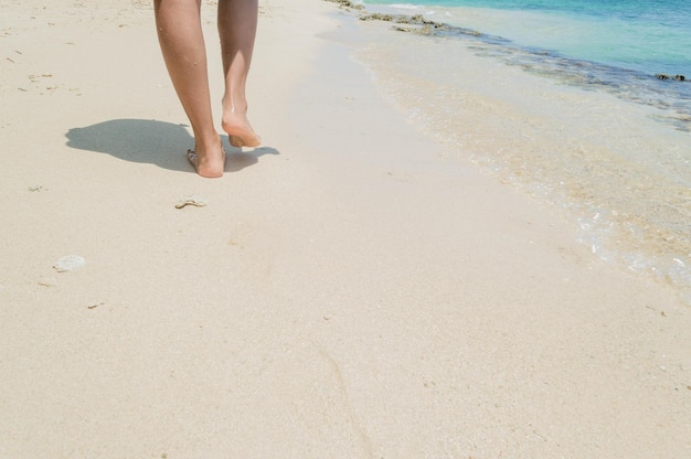 Photo pieds féminins marchant sur une belle plage isolée. empreintes de pas dans le sable sur la plage