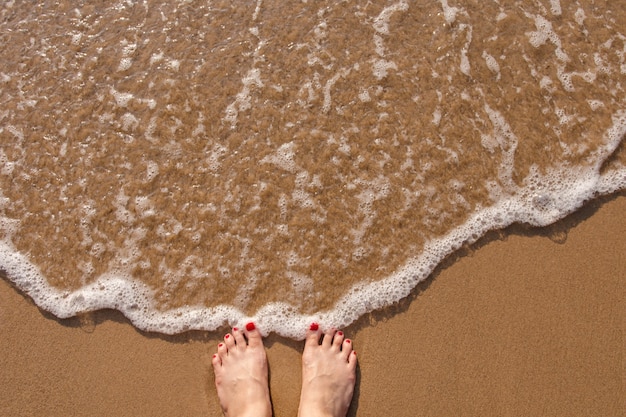 Pieds de femme debout sur la plage de sable d&#39;été