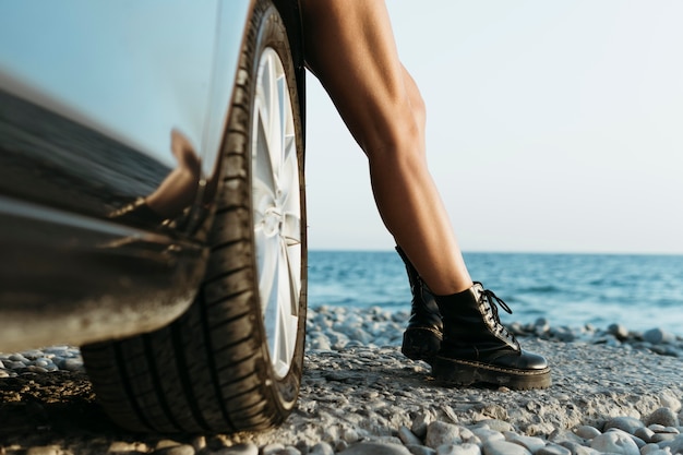 Photo pieds de femme debout en voiture près de la mer