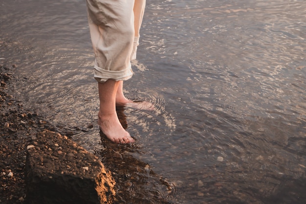 pieds de femme marchant dans l'eau de la rivière ou de la mer au coucher du soleil l'heure d'été