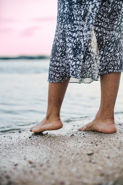 Photo les pieds d'une femme se tiennent sur la plage photo