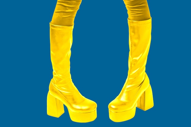 Pieds de femmes en bottes dorées à semelles hautes sur fond bleu Photo promotionnelle de chaussures à la mode