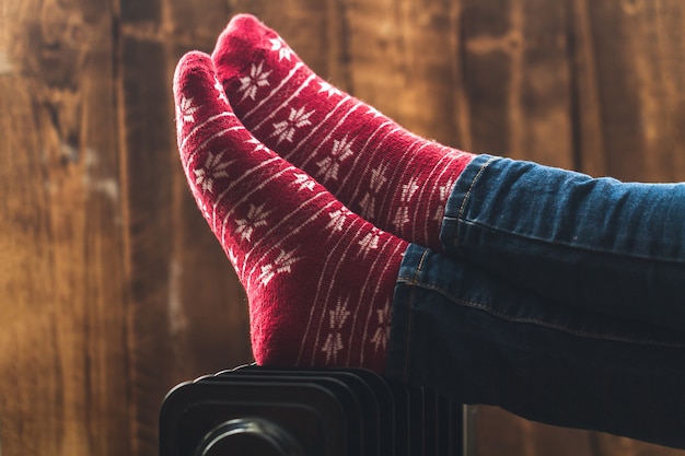 Photo pieds des femmes à noël, chaussettes chaudes et hivernales sur le radiateur. garder au chaud en hiver, les soirées froides. saison de chauffage