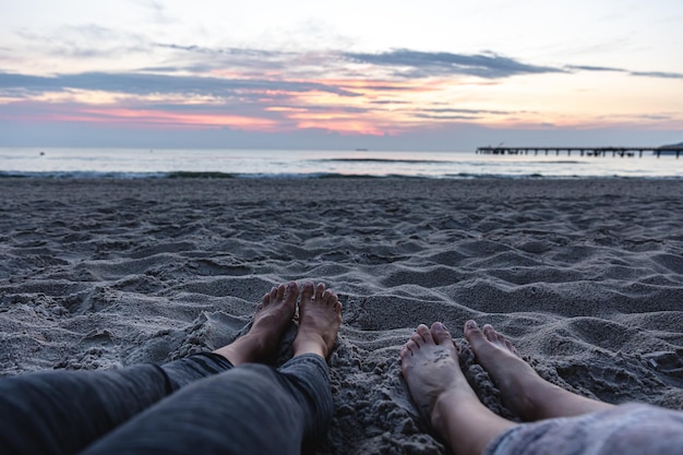 Pieds de femmes sur le sable au bord de la mer au coucher du soleil