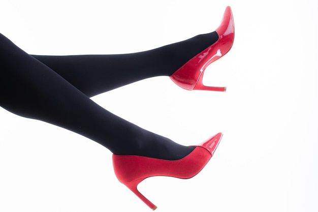 Pieds d'une fille en collants avec des chaussures rouges sur fond blanc