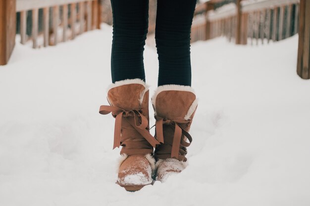 Pieds de fille dans des bottes chaudes en hiver sur le sol enneigé