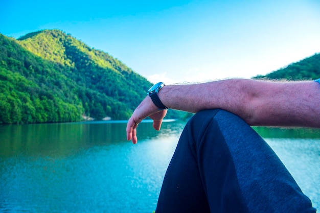 Les pieds d'un homme assis près du lac