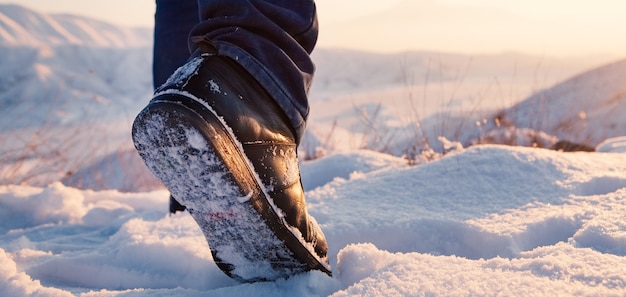 Pieds d'hommes en bottes dans la neige marchant en hiver