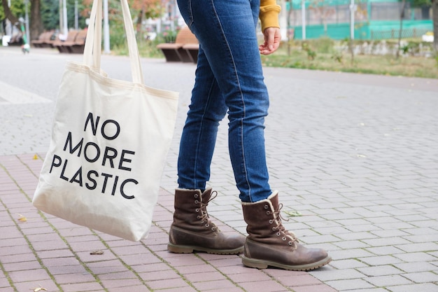 Des pieds humains et un sac réutilisable avec l'inscription No more plastic