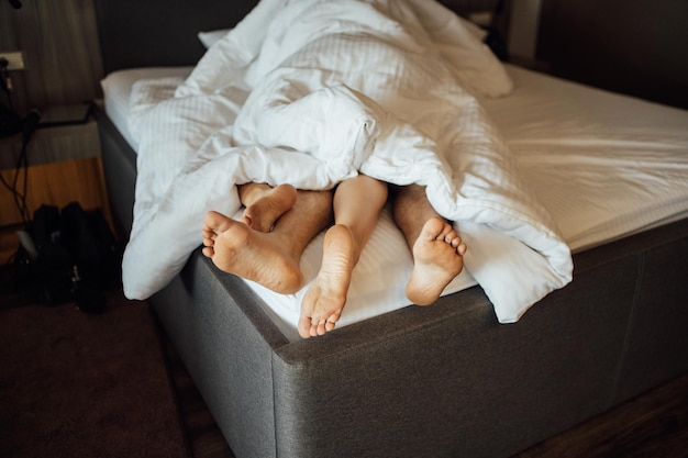 Les pieds d'un jeune couple hétérosexuel se relaxant au lit.